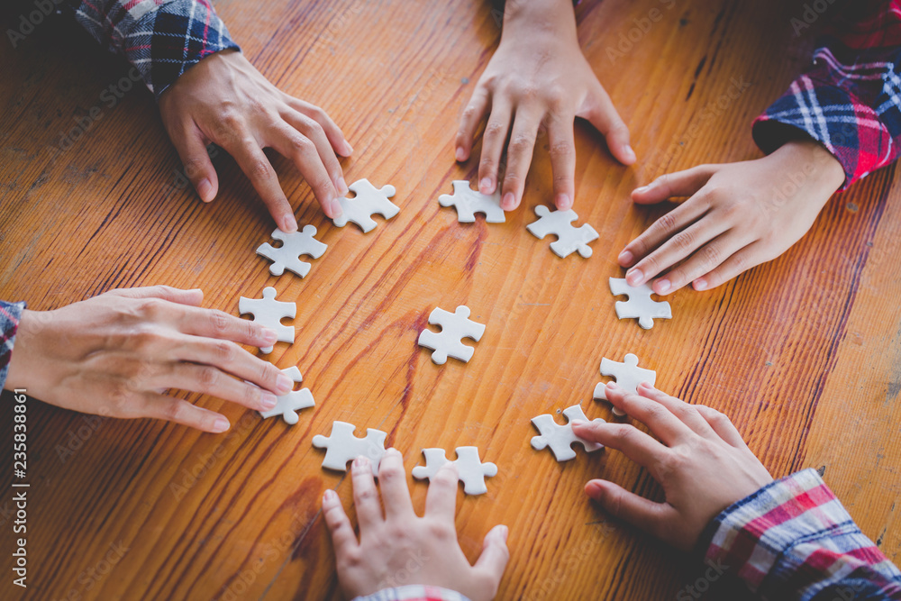 Hands of diverse people assembling jigsaw puzzle, Youth team put pieces together searching for right match, help support in teamwork to find common solution concept, top close up view Hands of diverse people assembling jigsaw puzzle, Youth team put pieces together searching for right match, help support in teamwork to find common solution concept, top close up view