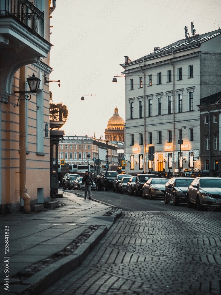 The Golden dome of St. Isaac's Cathedral in St. Petersburg looks out from behind the city landscape, in the evening, overcast