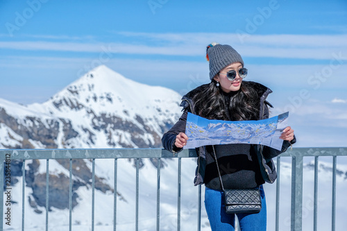 Young female tourist looking map at Schilthorn in Switzerland with a magnificent panoramic view of the Swiss Skyline. photo