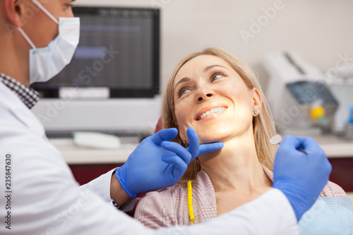 Cheerful mature woman smiling happily at her dentist during medical examination. Happy female patient enjoying painless teeth examination by professional dentist. Happiness, health, dentistry concept