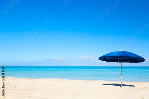 Blue beach umbrella parasol on the tropical beach. Vacation background.