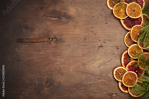 Dark brown vintage rustic wooden background with fir branches, dried orange and grapefruit rings