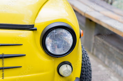 close up of yellow retro car with round headlights