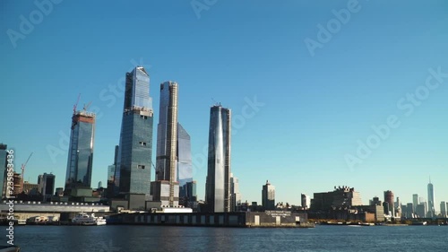 A New York city landscape in daytime from the floating boat huge skyscrapers shining in clear sky slowmo.