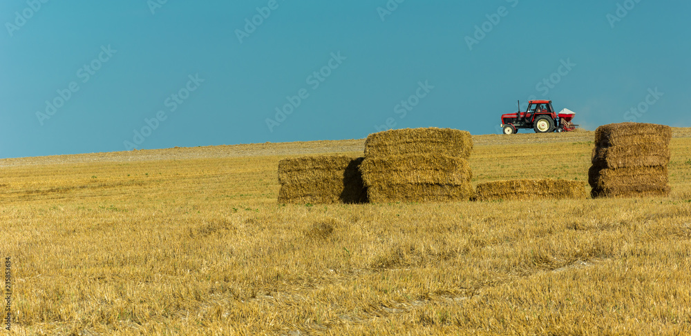 Tractors driving on the field and hay stacks