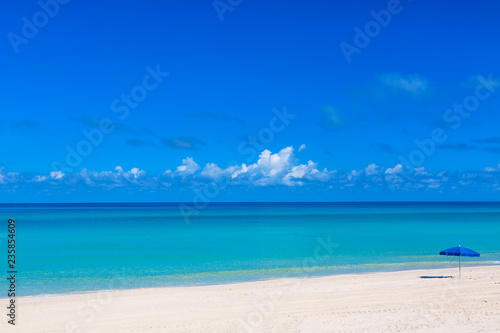 Blue beach umbrella parasol on the tropical beach. Vacation background. Idyllic beach landscape.