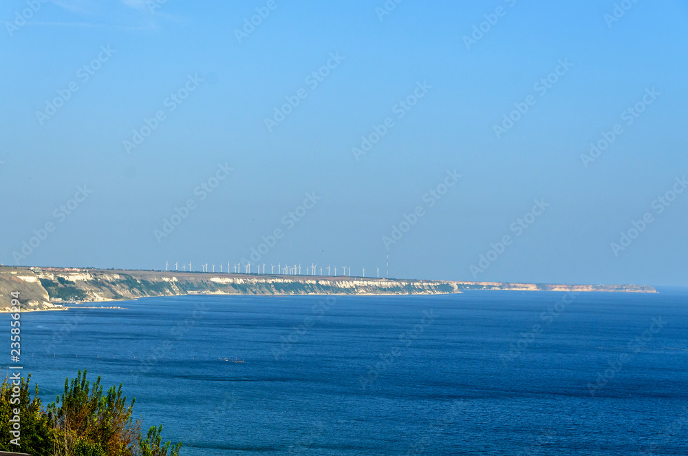 Thracian cliffs near blue clear water of Black Sea, wind farm