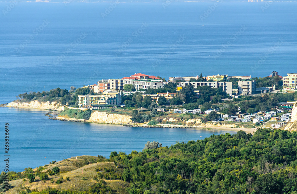Green Thracian cliffs near blue clear water of Black Sea, bulgarian coastline with hotels
