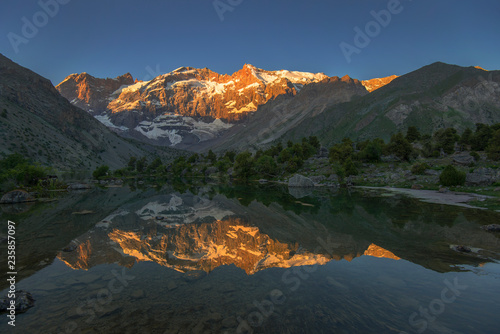 Sunlit mountain reflecting in lake
