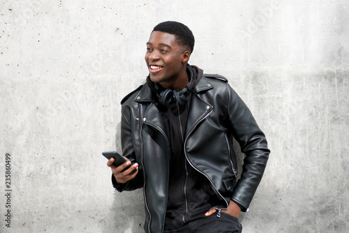 Photos young black man in leather jacket smiling while holding cellphone