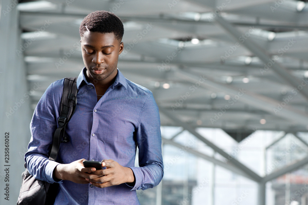 young african american businessman with bag looking at cellphone young african american businessman with bag looking at cellphone