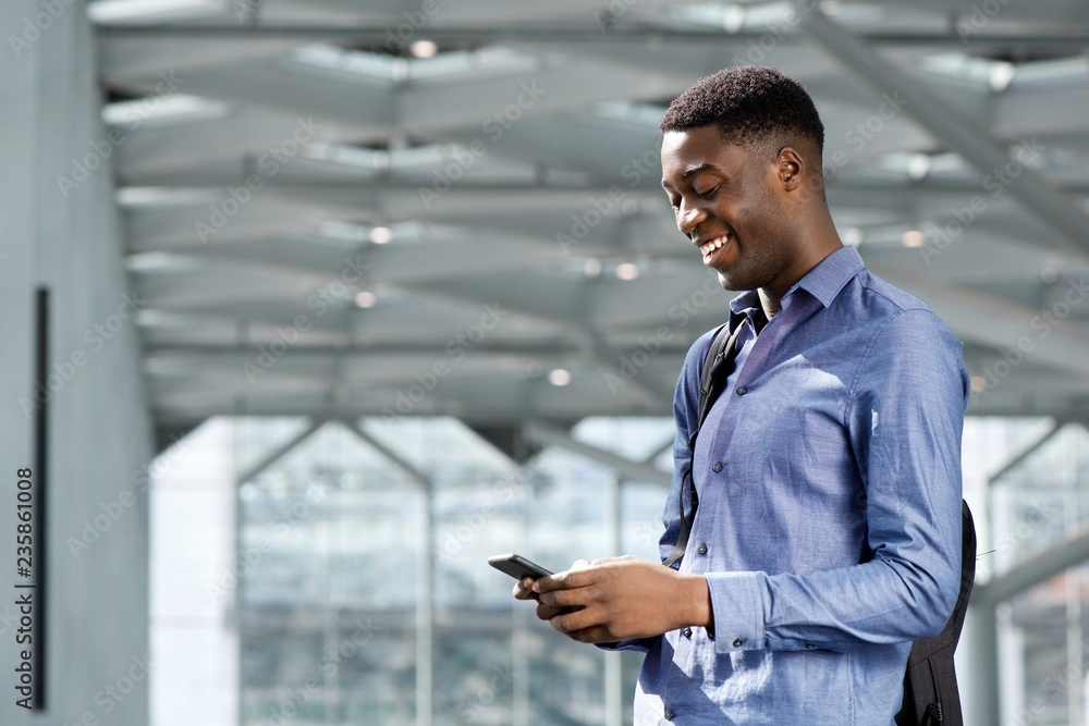 Side of happy young black businessman looking at cellphone Side of happy young black businessman looking at cellphone