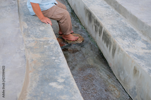 man soaking feet in hot mineral spring water © 88studio