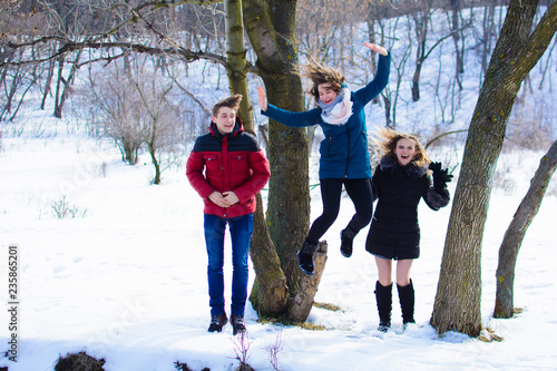 group of friends jumping together in the park in winter