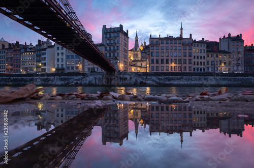 Old bridge over the Saone river reflected in a puddle during a pink sunset in Vieux-Lyon, Lyon.