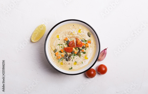 Lentil soup puree with tomatoes, cucumber and nuts in a bowl on a white wooden background