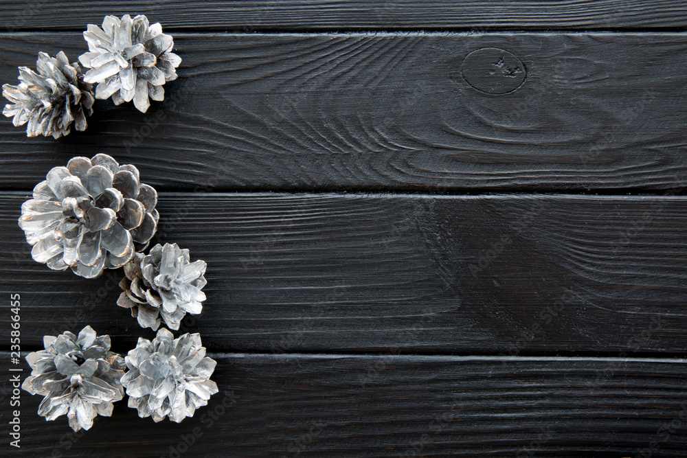 Silver pine cones on black wooden table background. Space for text. Silver pine cones on black wooden table background. Space for text.