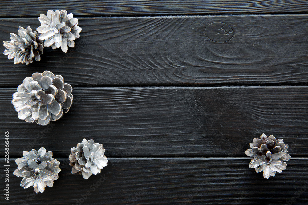 Silver cones on black wooden table background. Space for text. Top view. Silver cones on black wooden table background. Space for text. Top view.