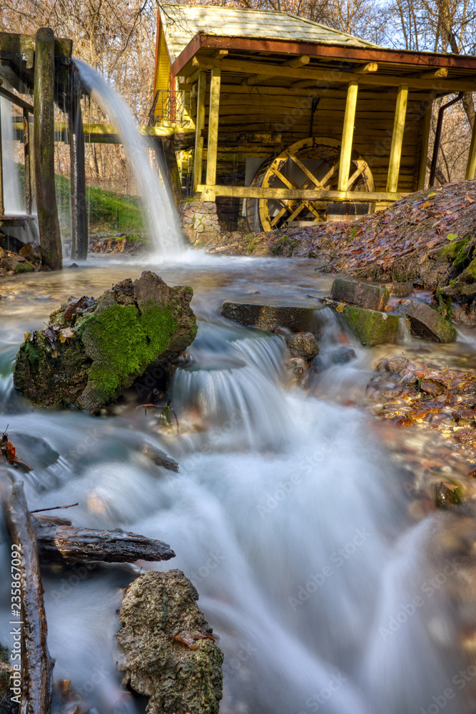 Naklejka premium A stream of flowing clean spring water in an old mill. Photo taken in autumn in Russia.