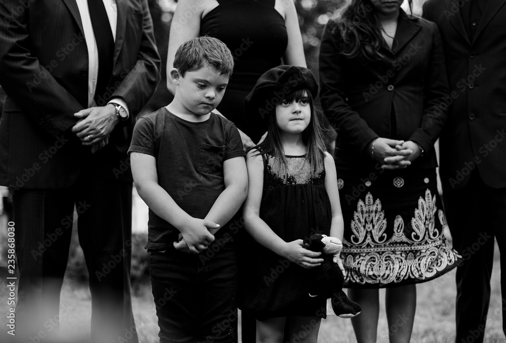 Obraz premium Sad grandkids standing by the grave