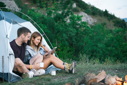 Smiling young couple using tablet computer on a camping 