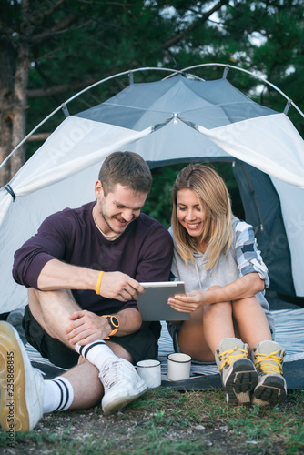 Smiling young couple using tablet computer on a camping  photo