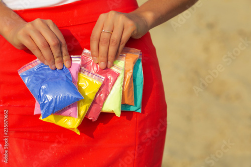 Female hands holding bags of dry colorful paint Holi. Empty space