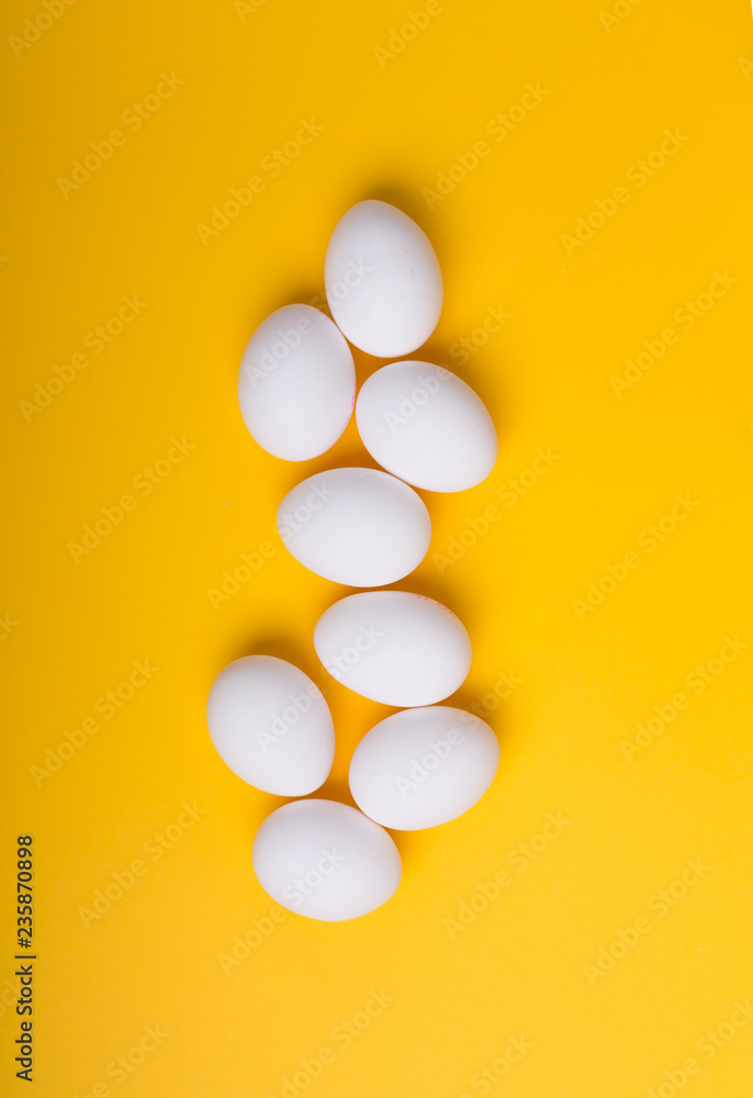 White eggs on the yellow background. Vertical orientation