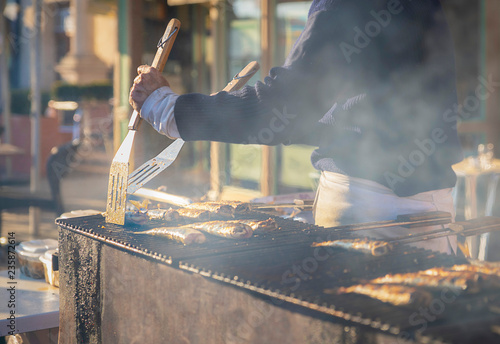 Fototapeta Naklejka Na Ścianę i Meble -  Man cooks herring on a grill on the market