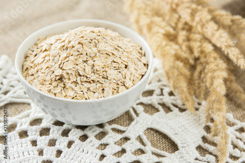Oatmeal in white bowl with spikes on textile background. Healthy eating