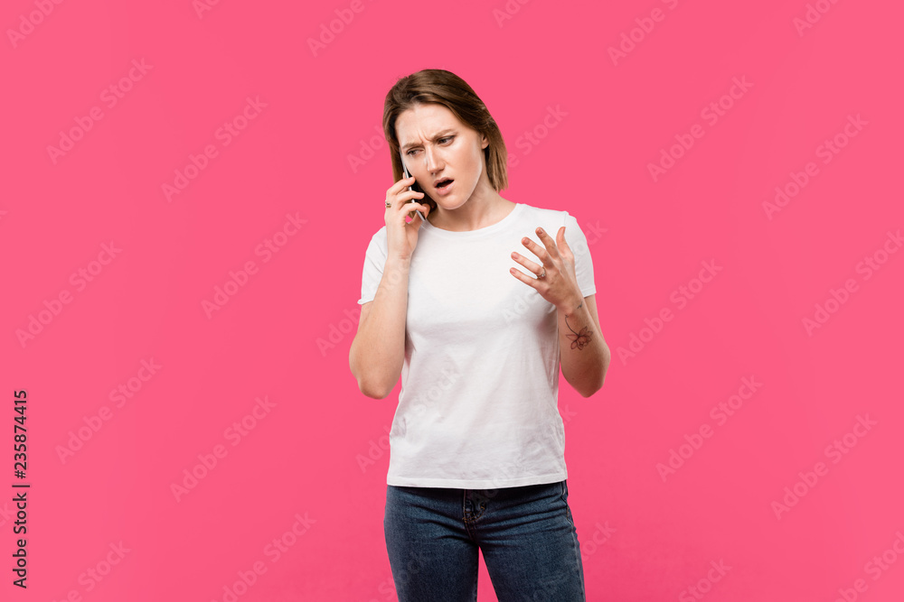 angry girl talking on smartphone and gesturing by hand isolated on pink angry girl talking on smartphone and gesturing by hand isolated on pink