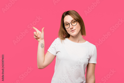 happy stylish girl with tattooed hand pointing by finger isolated on pink © LIGHTFIELD STUDIOS