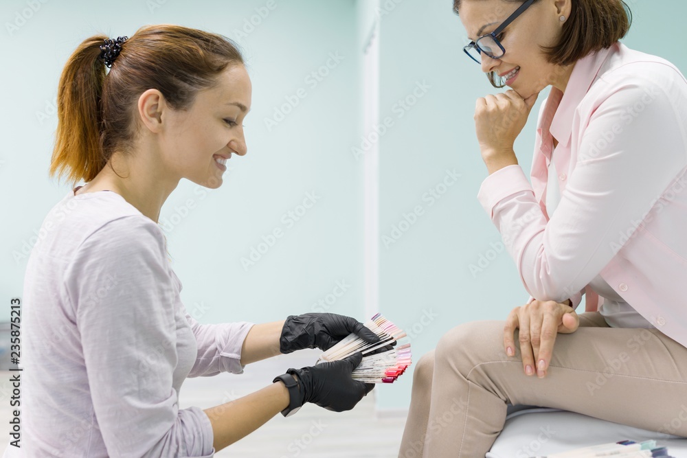Young beautician in beauty nail salon doing pedicure, paints nails. Nail care in beauty salon Young beautician in beauty nail salon doing pedicure, paints nails. Nail care in beauty salon