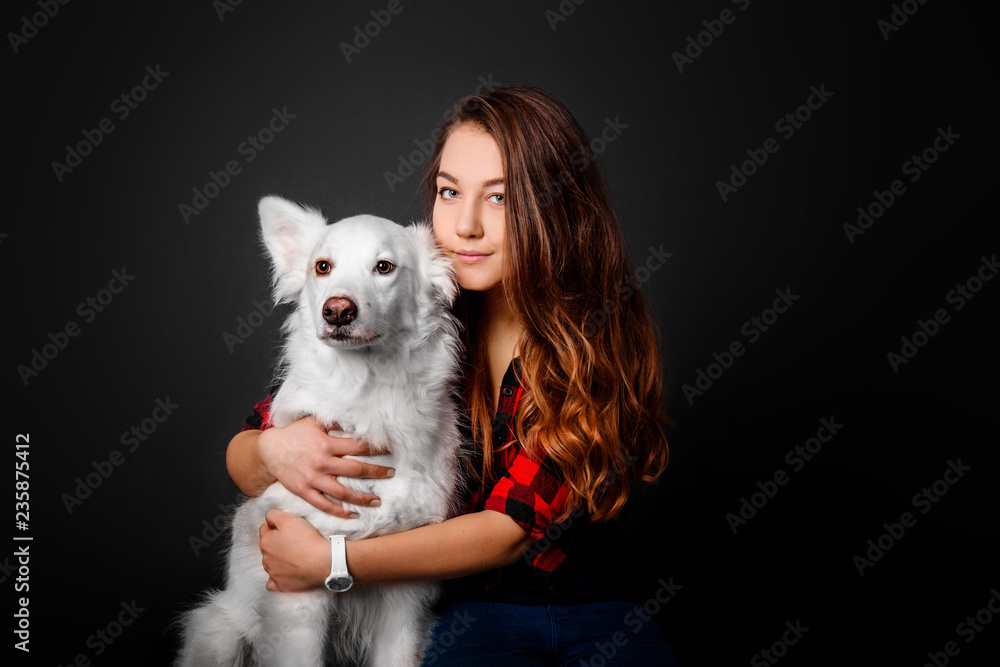 Portrait of a young teenager girl with her dog in studio on a black background Portrait of a young teenager girl with her dog in studio on a black background