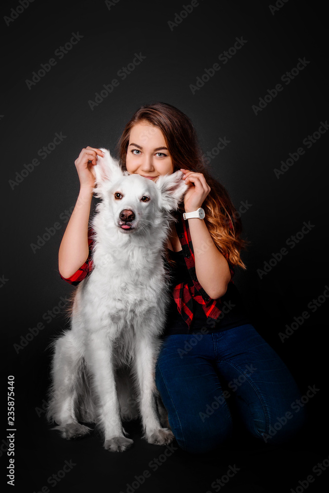 Portrait of a young teenager girl with her dog in studio on a black background Portrait of a young teenager girl with her dog in studio on a black background