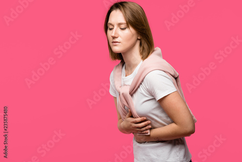 stylish girl having stomach pain isolated on pink