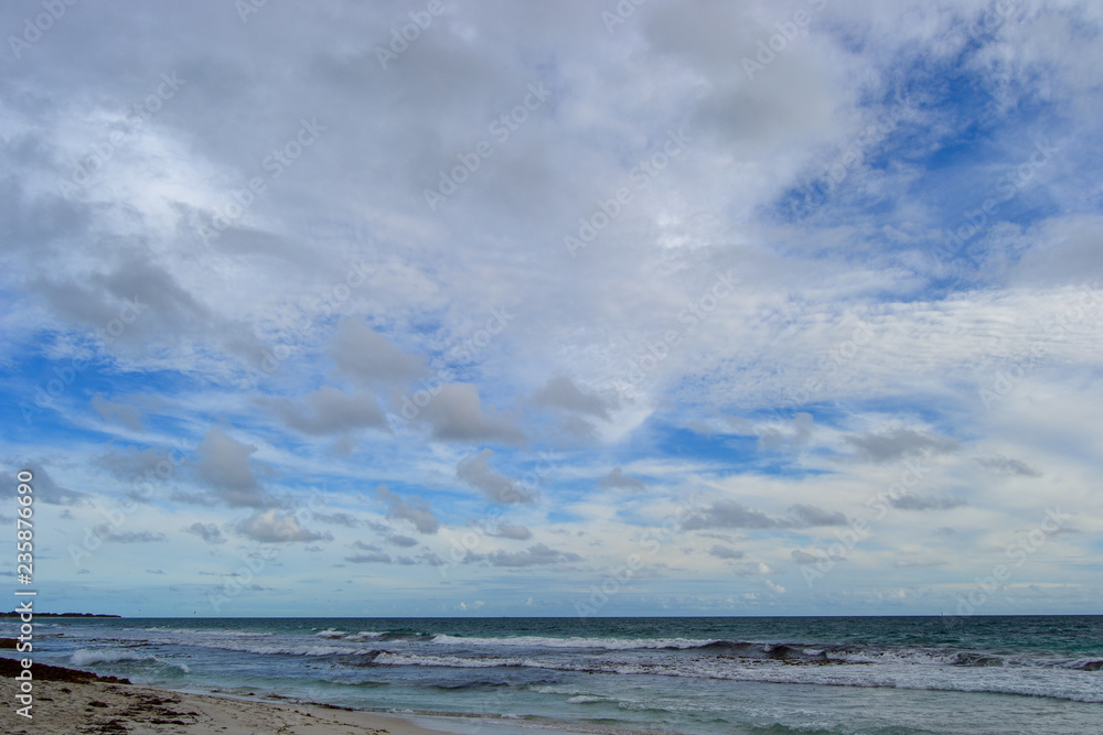 Landscape of a beach at sunset with clouds and ocean in the horizon