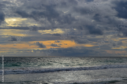 Landscape of a beach at sunset with clouds and ocean in the horizon