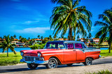 Amerikanischer roter Ford Oldtimer parkt am Strand unter Palmen in Varadero Cuba - Serie Cuba Reportage