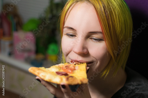 A woman of 30-40 years old is eating pizza and smiling.