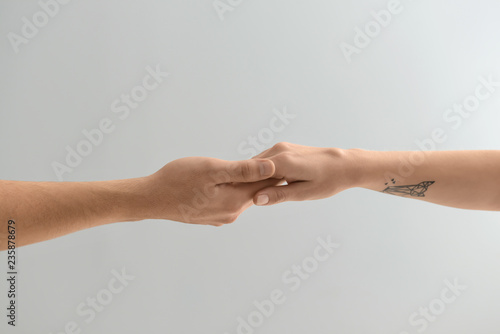 Man and woman holding hands on light background