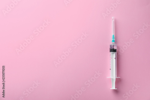 Syringe with liquid on color background