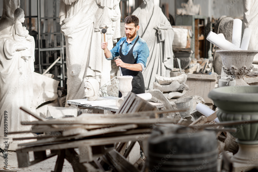 Sculptor working at the atmospheric old workshop with sculptures and trash Sculptor working at the atmospheric old workshop with sculptures and trash