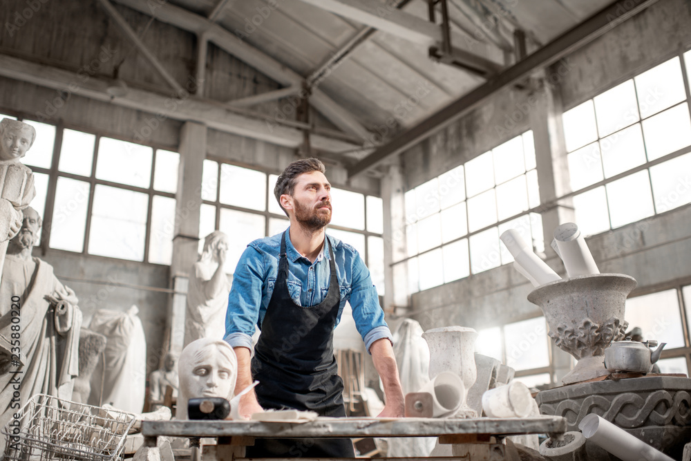Φωτογραφία Portrait of a handsome male sculptor at the working place in the old atmospheric
