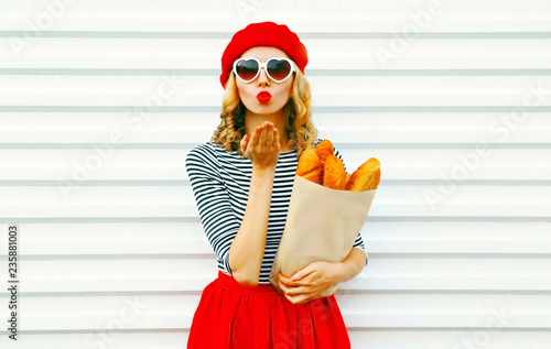 Obraz na płótnie Portrait beautiful woman sends sweet air kiss wearing red beret holding paper ba