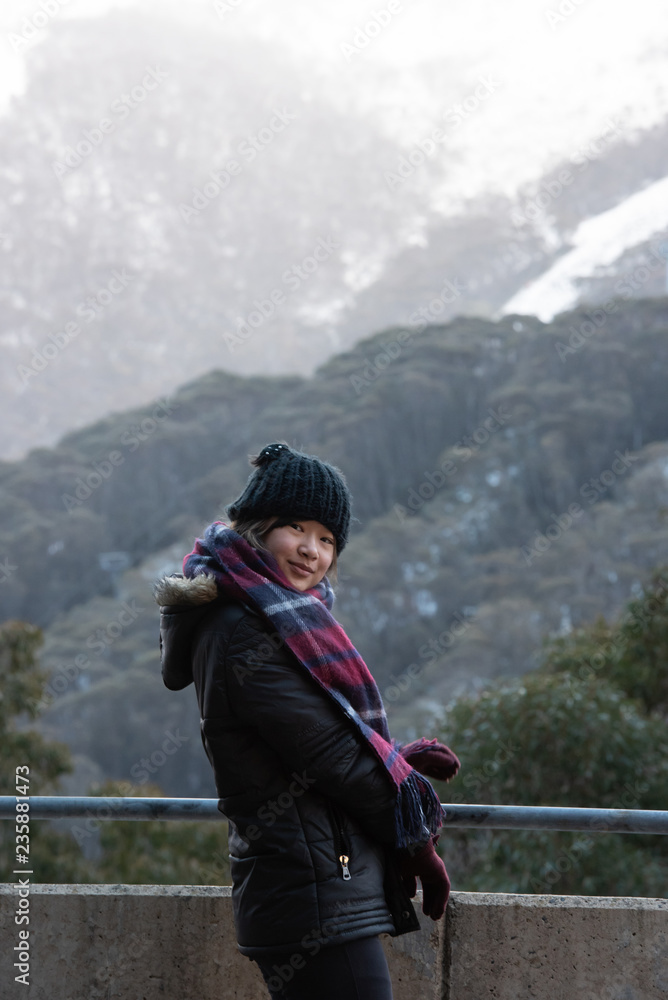 Young woman posing in front of snow covered Mount Kosciuszko at Thredbo