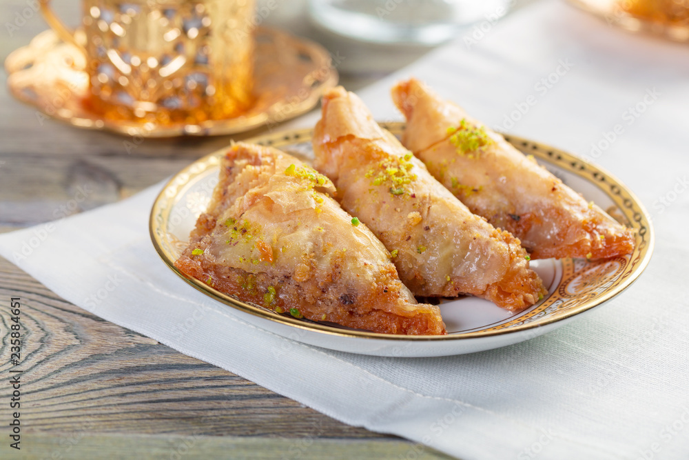 Traditional arabic dessert baklava with cashew, walnuts and cardamom with an eucalyptus branch on a wooden table Traditional arabic dessert baklava with cashew, walnuts and cardamom with an eucalyptus branch on a wooden table