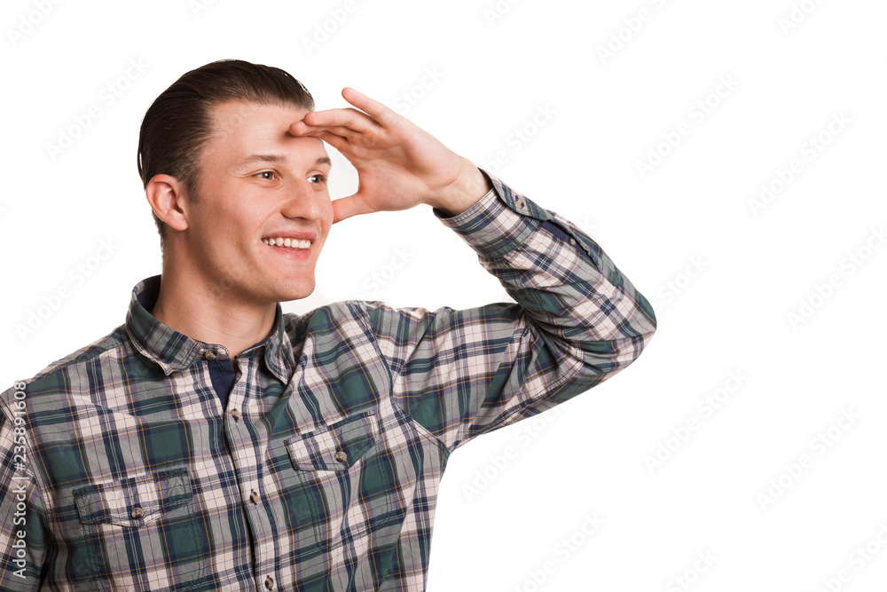 Studio shot of a handsome young man smiling joyfully, looking away thoughtfully isolated on white. Attractive young man posing with a hand to his eyes, waiting for something, copy space Studio shot of a handsome young man smiling joyfully, looking away thoughtfully isolated on white. Attractive young man posing with a hand to his eyes, waiting for something, copy space