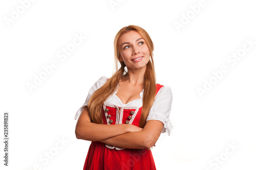 Beautiful Bavarian waitress smiling looking at the copy space on the side posing isolated on white. Sexy Oktoberfest girl in traditional german dress posing gracefully. Celebration, festivity concept photo