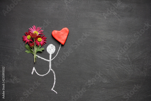 Chalk drawing man with bouquet of flowers and big red heart on chalkboard background with copy space. Valentines day gift or declaration of love concept